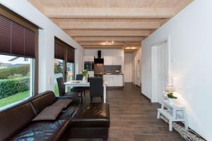 a living room with a leather couch and a kitchen at Ferienwohnung Tiefenbach in Hürtgenwald