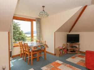 een eetkamer met een tafel en stoelen en een televisie bij Cooinda Flat in Morar