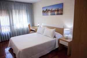 Pokój hotelowy z białym łóżkiem i oknem w obiekcie Laros Pios Alojamiento w mieście Villalba