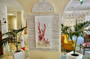 a lobby with two potted plants and a painting on a wall at Hotel Corallo Garnì in Cattolica