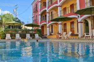 a swimming pool in front of a building with chairs and umbrellas at La Casona Tequisquiapan Hotel & Spa in Tequisquiapan