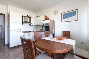kuchnia z drewnianym stołem i jadalnią w obiekcie Apartmani PARADISO w Krku