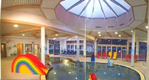 a large indoor pool with a rainbow in the ceiling at Zillerglückhütte - 5 Sterne Camping Aufenfeld in Aschau