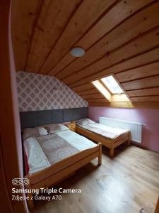 two beds in a room with a wooden ceiling at Pokoje i apartamenty u Bartka in Szczawnica