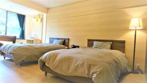 1 dormitorio con 2 camas y lámpara en ファスティングホテル海の杜, en Kannami