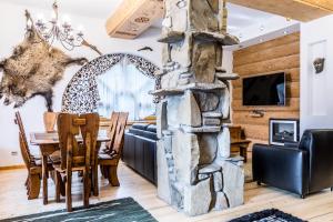a dining room and living room with a stone fireplace at Apartament Harnasiowa Grota in Kościelisko