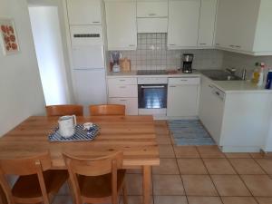 cocina con mesa de madera y armarios blancos en Casa Laura en Cevio