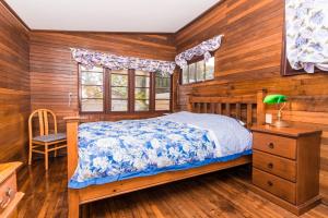 a bedroom with a bed and wooden walls and windows at Chestnut Brae Farmstay - Chestnut Retreat in Nannup
