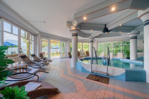 a swimming pool in a room with chairs at Hotel Alexanderhof in Millstatt