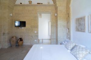 a bedroom with a white bed in a stone wall at Li Perrini Boutique B&B in Acquarica
