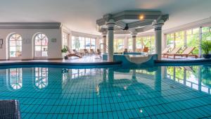 a swimming pool with blue tiles in a building at Hotel Alexanderhof in Millstatt
