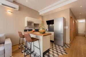 a kitchen with a counter with stools and a refrigerator at Le Paradis d Elsa in Beaune