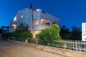 une grande maison blanche avec un panneau devant elle dans l'établissement Apartments Villa Filip, à Trogir