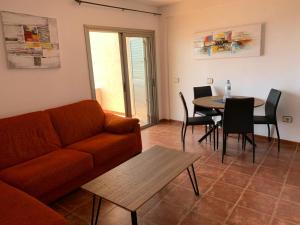 uma sala de estar com um sofá e uma mesa com cadeiras em Nice terrace in front of the sea. La Jaquita em El Médano