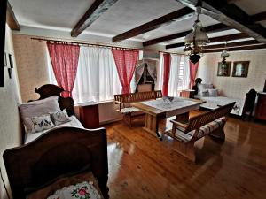 a living room with a table and chairs and red curtains at Apartment Slavonska Kuća in Pleternica