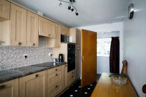 una cocina con armarios de madera y encimeras negras en Mews Flat, en Tenby