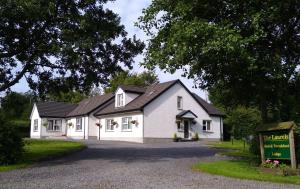 a white house with a black roof and a driveway at The Laurels Bed & Breakfast Lodge in Omagh