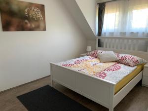 ein Schlafzimmer mit einem weißen Bett mit Kissen und einem Fenster in der Unterkunft Steira-Studios in Ehrenhausen
