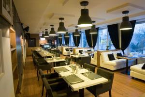 a restaurant with tables and couches and chairs and tablesearcher at Astrum Palace in Mažeikiai