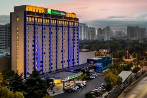 郑州河南中州智选假日酒店的一座酒店大楼,在城市前设有停车场