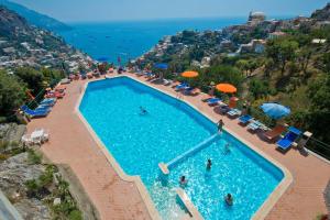 una piscina con sillas y sombrillas y el océano en Casa Giostrello, en Positano
