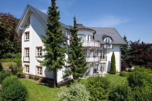 una gran casa blanca con un árbol en el patio en Villa Katharina Penthouse Wohnung, en Willingen