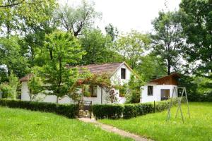 a small white house in a field with a swing at Una Rosa Hostel in Bihać
