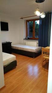 een slaapkamer met 2 bedden, een tafel en een raam bij Apartament na Cisowej in Słupsk