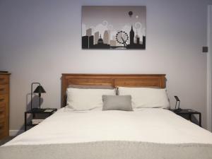 um quarto com uma cama grande com lençóis brancos e um quadro em Switchback Stays Marina Apartments em Cardiff