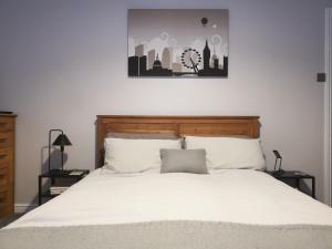 a bedroom with a large bed with white sheets and a painting at Switchback Stays Marina Apartments in Cardiff