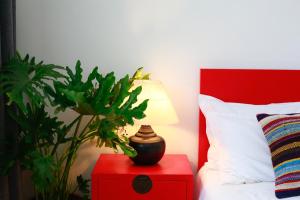 um quarto com uma mesa de cabeceira vermelha com um candeeiro e uma planta em Peking Youth Hostel em Pequim