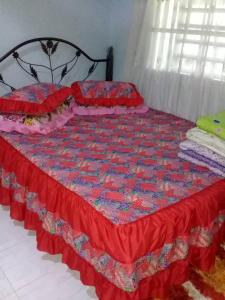 a bed with a red and blue quilt on it at AMIMAS HOMESTAY in Kampong Bagan Samak
