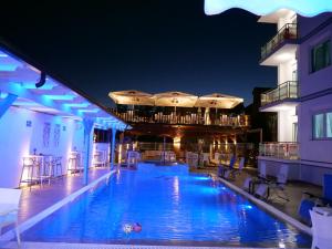 una piscina por la noche con sillas y sombrillas en Brian Hotel, en Velipojë