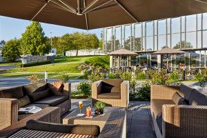 eine Außenterrasse mit Sofas, Tischen und Sonnenschirmen in der Unterkunft LÉGÈRE HOTEL Wiesbaden-Taunusstein in Wiesbaden