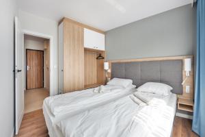 - une chambre avec un grand lit et des draps blancs dans l'établissement Apartamenty Sun & Snow Bel Mare, à Międzyzdroje