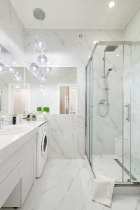 a white bathroom with a shower and a washing machine at Avangard DeLuxe Art Apart in Lviv