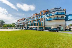 a large building with cars parked in front of it at Apartamenty Sun & Snow Bel Mare in Międzyzdroje