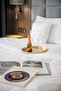 a tray with a bottle of champagne and two glasses on a bed at DB Hotel Wrocław in Wrocław