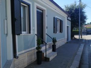 a white house with two potted plants on the sidewalk at B&B TrentaQuattro in Campomarino