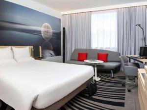 Novotel York Centre في يورك: غرفة فندقية بسرير كبير واريكة