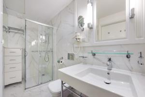 a white bathroom with a sink and a shower at Prywatne Apartamenty Sun & Snow w Baltic Park Fort in Świnoujście