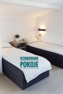 two beds in a room with a sign on it at Dom Wypoczynkowy Oliwka in Ustka