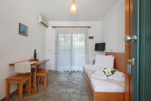 a room with a bed and a desk and a table at Maistrali Apartments in Ormos Panagias