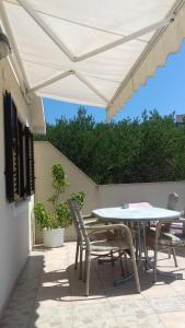 a patio with a table and chairs under a white umbrella at Apartmani Anamar in Supetarska Draga