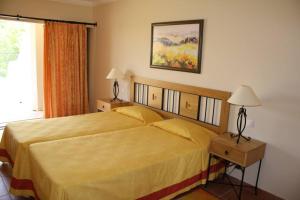 a bedroom with a bed and two lamps and a window at Apartamento T1 - Praia Senhora da Rocha in Porches
