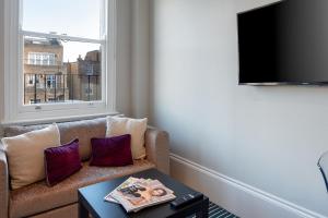 a living room with a couch and a tv at CAPITAL Sloane Street Studio with Balcony in London