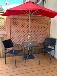 a table with two chairs and a red umbrella at Le 154 Jacques-Cartier in Gaspé