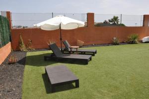 a patio with two chairs and an umbrella at ECO Villa White Suite with climatized pool in Caleta De Fuste