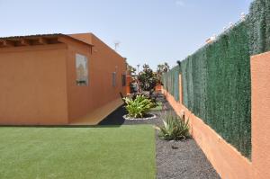 a retaining wall with a green hedge at ECO Villa White Suite with climatized pool in Caleta De Fuste