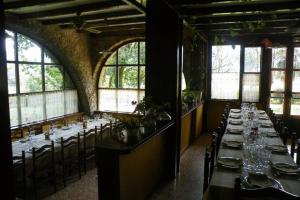 un comedor con mesas largas, sillas y ventanas en Allotjaments Colomer-Cullell, en Bas